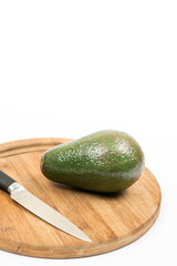 Avocado fruit on the wooden kitchen board with knife