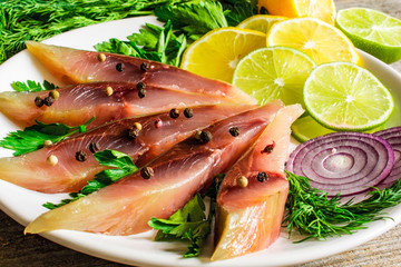 Fototapeta na wymiar salted fish fillet with herbs, lemon and spices in a plate