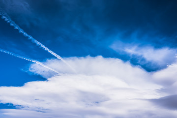 Dramatic HDR blue sky with huge fluffy white clouds and jet traces, tracks