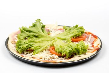 Preparing pizza with lettuce and tomato over white background