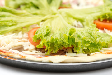 Preparing pizza with lettuce and tomato over white background