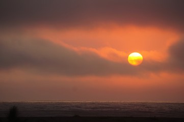 heavy sun with  dark clouds sunset over the ocean