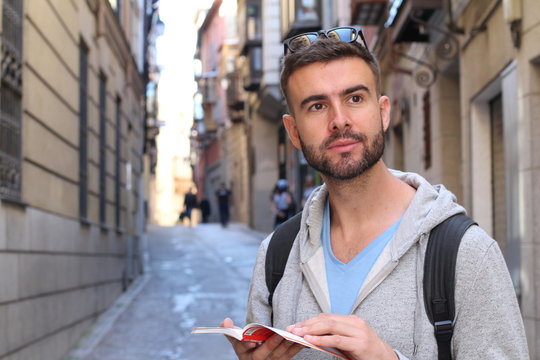 Handsome tourist consulting a guide during a travel around Europe