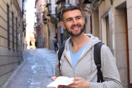 Joyful tourist holding map or dictionary during a vacation