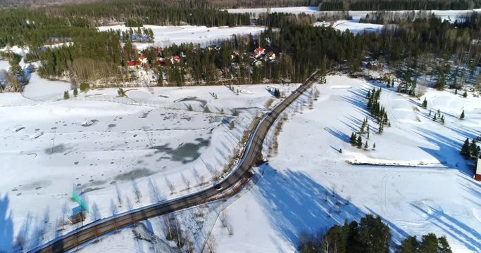 Cars driving on R&ouml;yl&auml;ntie, Cinema 4k aerial view of a few cars on a winter road, near lake Bodom, in Espoo, Finland