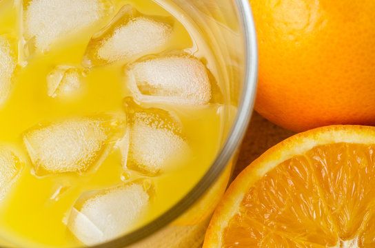 Glass of Fruit Juice with Ice Cubes and Oranges