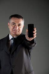 Naklejka premium Serious businessman holding up a smartphone