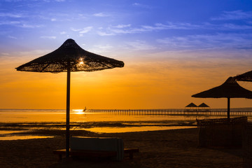 Sunrise at the sea with silhouette of beach umbrellas