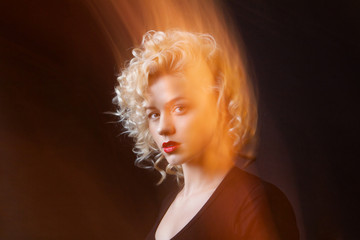 Portrait of a attractive woman with blonde curly hair in mixed light