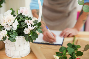 Obraz na płótnie Canvas Wicker basket with white azalea flowers on florist table