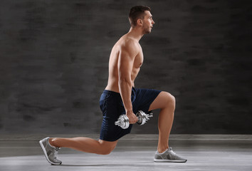 Obraz premium Sporty man doing exercises with dumbbells in gym