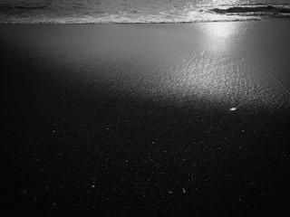 Black abstract natural sandy beach closeup, volcanic seacoast background. Space surface for text