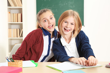 Fototapeta premium Two cute girls sitting at desk in school class