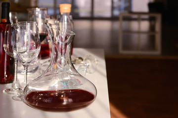 Decanter with red wine and glasses on table against blurred background