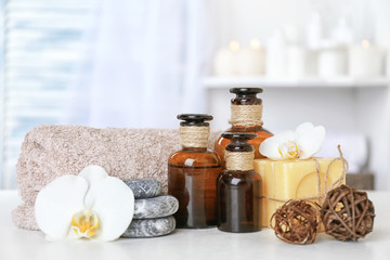 Spa set with aroma oils, soap, pebbles and flower on table