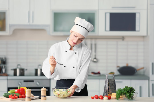 Female chef adding oil to vegetable salad in kitchen