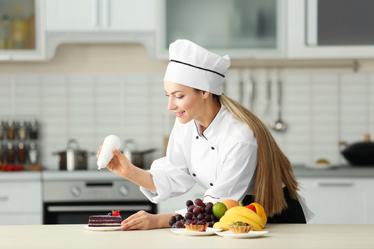 Female chef decorating cake in kitchen