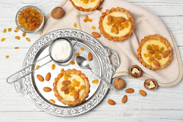 Delicious crispy tarts with almond and raisins on wooden table