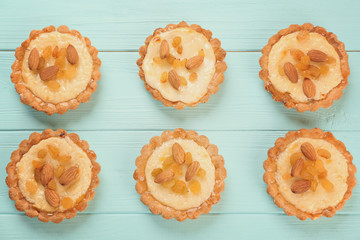 Delicious crispy tarts with almond and raisins on wooden background