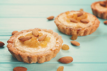 Delicious crispy tarts with almond and raisins on wooden background