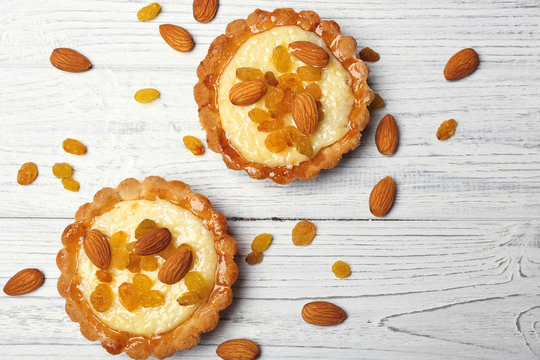 Delicious crispy tarts with almond and raisins on wooden background