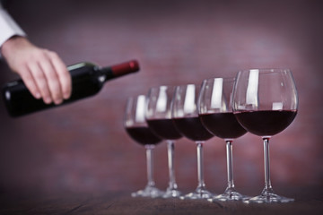 Waiter serving wine on color background