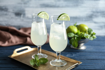Tray with refreshing cocktails and lime on wooden table