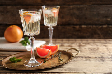 Tray with refreshing cocktails and grapefruit on wooden table