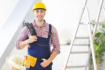Young electrician standing near stepladder