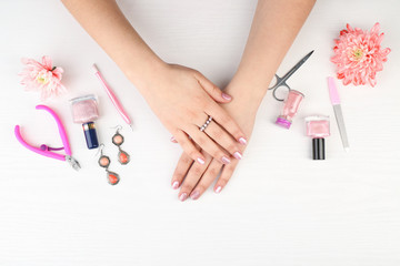 Nail art concept. Female hands with beautiful manicure and instruments on white wooden background
