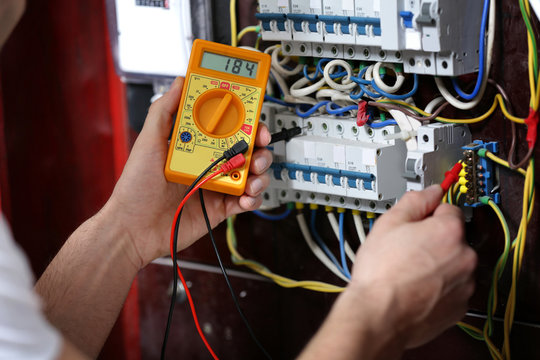 Electrician measuring voltage in distribution board, closeup