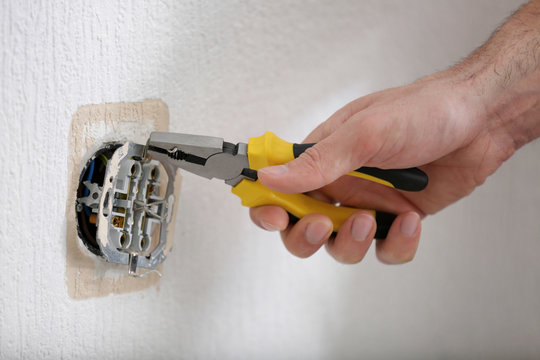 Hands of electrician installing socket, closeup