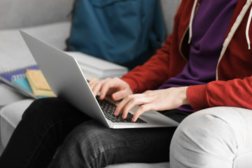 Teenager working with laptop at home, closeup