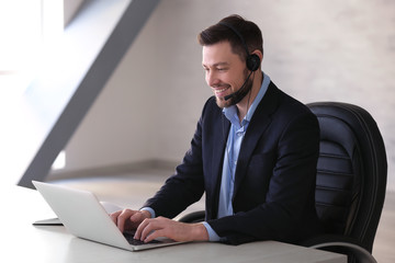 Young man with headset and laptop working in office © Africa Studio