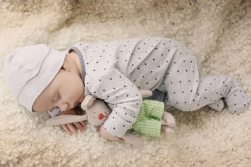 Cute little baby with bunny toy sleeping on plaid at home