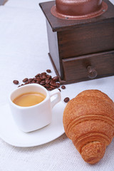 Crispy fresh croissants and cup of coffee espresso on a white background, morning breakfast, selective focus