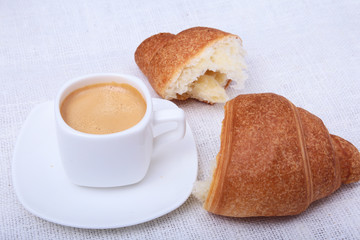 Crispy fresh croissants and cup of coffee espresso on a white background, morning breakfast, selective focus