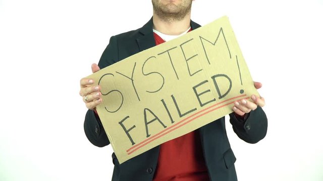 Man holding a System Failed cardboard protest sign