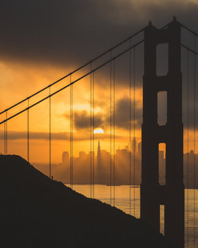 View of Golden Gate Bridge with city in background during sunset