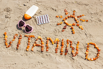 Medical pills, inscription vitamin D and accessories for sunbathing on sand at beach, summer time...