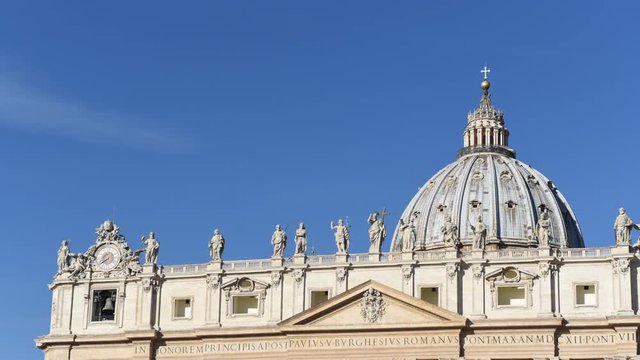 View of Vatican St.Peter basilica facade and dome with sunrise light on clear blue sk, timelapse and slow pan from left to right