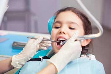 Fototapeta premium Close-up of pretty little girl opening his mouth wide during treating her teeth by the dentist