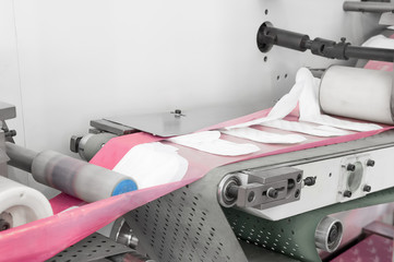 factory and equipment for the production of female sanitary napkins. women hygiene pads on a conveyor belt closeup