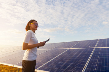 woman engineer working on checking checking status equipment at solar power plant with tablet...