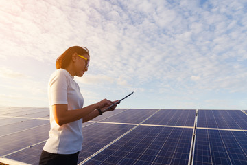 woman engineer working on checking checking status equipment at solar power plant with tablet...