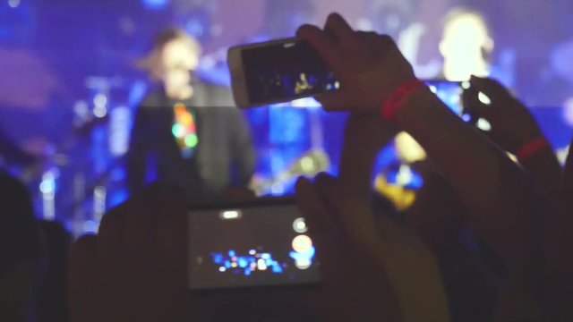 Fans hands recording video and taking pictures with smart phones at music concert. People crowd partying at rock concert in a night club. 3840x2160