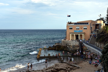 Sydney, Australia - Feb 5, 2017. Coogee Surf Life Saving Club and swimming pool with ocean view in summer time. People relaxing, swimming and sun bathing on Coogee beach.