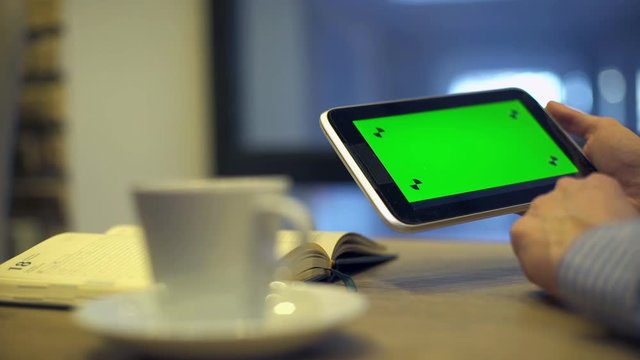 Man using Tablet with Green Screen in cafe. Video can be used in coffee house