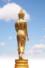 Golden Buddha statue from back side on white cloudy blue sky in sunny day - 140587640