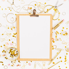 Beauty blog background. Clipboard and gold style feminine accessories pattern. Golden tinsel, scissors, pen, rings, necklace, bracelet on white background. Flat lay, top view.